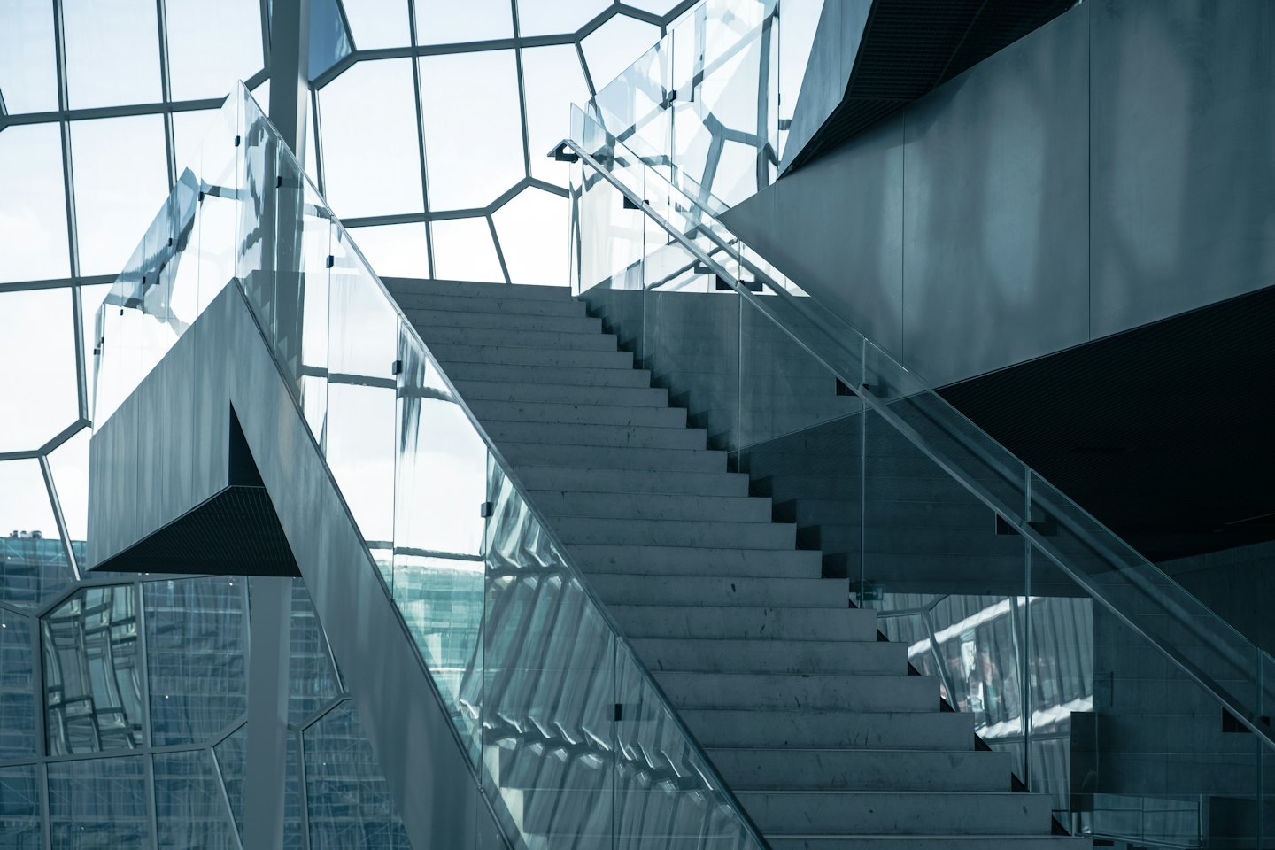 Große Betontreppe mit Glasgeländer in modernem Innenraum.