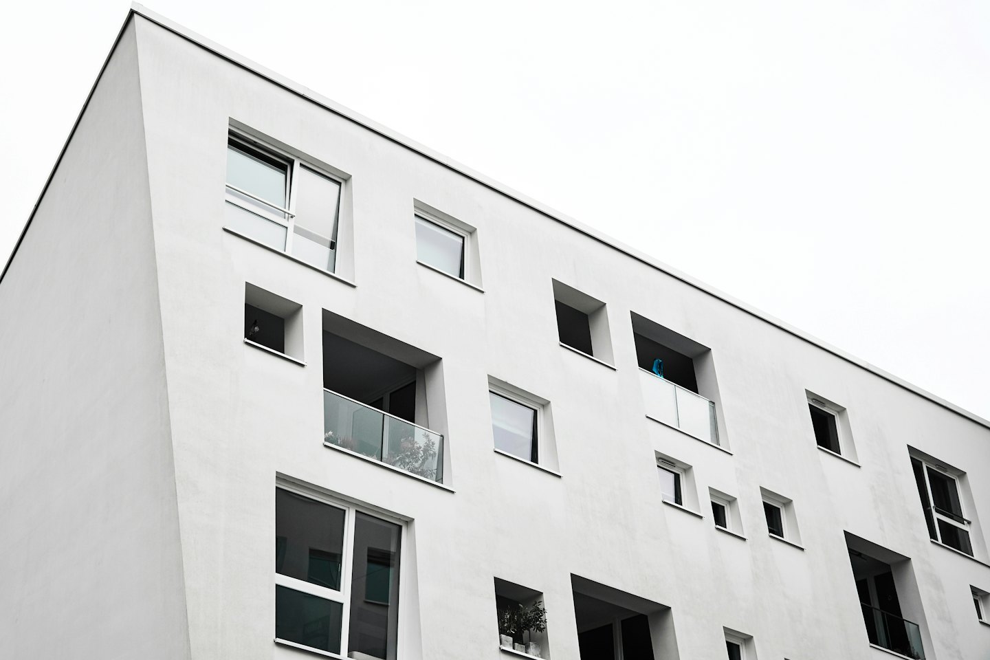 Modernes weißes Gebäude mit geometrischen Fenstern und Glasbalkonen.